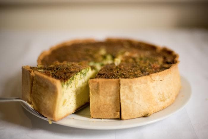 Zoutarme hartige taart met broccoli, brie en cashewnoten in stukken op een bord