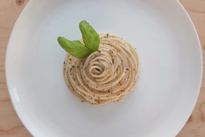 Zoutarme pasta met pulled chicken op een wit bord