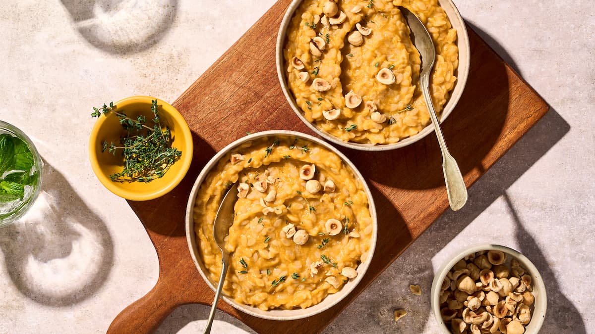 Orzo risotto met pompoen, geserveerd als romige orzoschotel met stukjes pompoen en kruiden in een kom