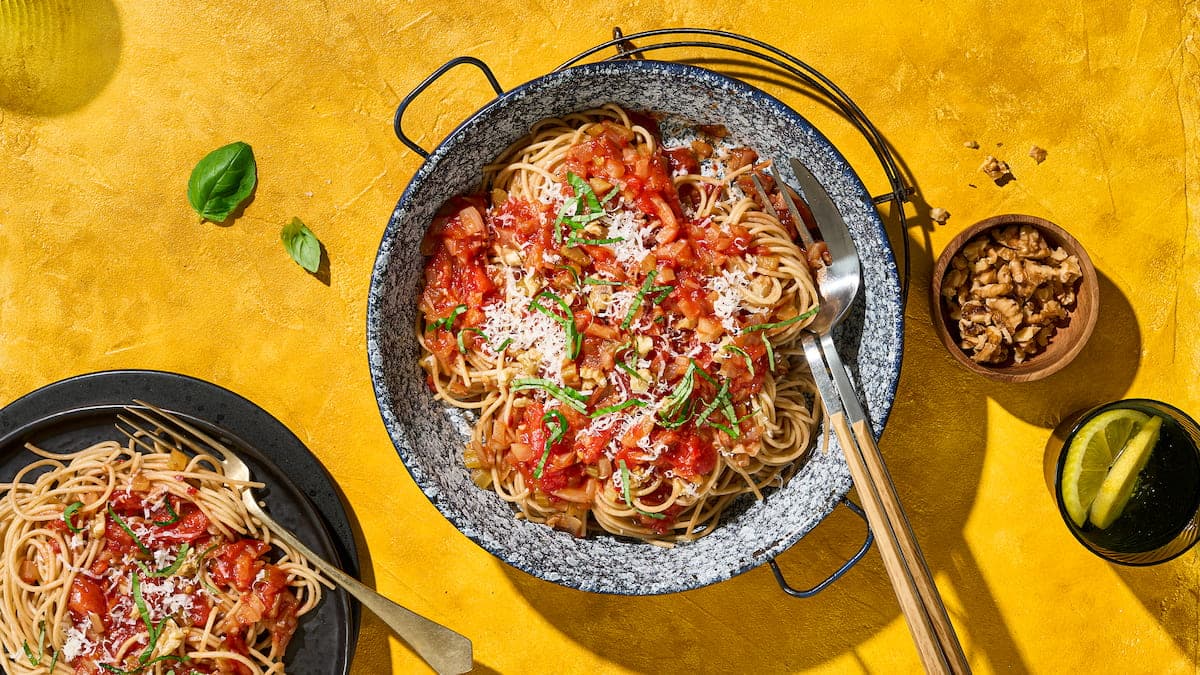 Spaghetti met tomaat en basilicum, geserveerd als pastagerecht met tomatensaus en verse basilicumblaadjes op een bord