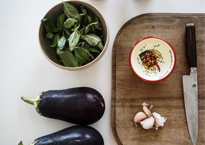 aubergine, kruiden en knoflook op snijplank