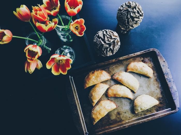 bakplaat met empanada's naast vazen met bloemen