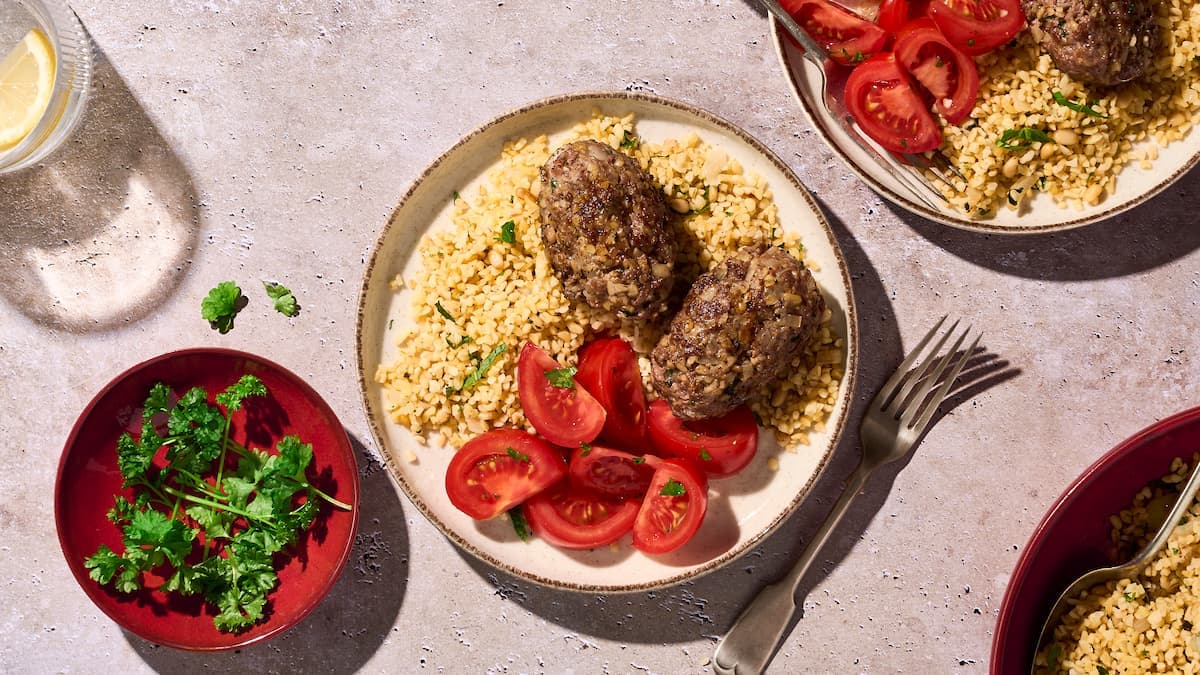 Gehaktballetjes met bulgur en tomatensalade geserveerd op een bord, met sappige balletjes, lichte bulgur en frisse salade