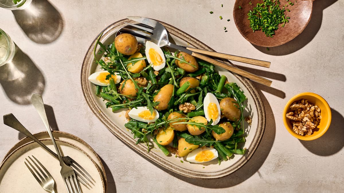 Krieltjessalade met sperziebonen, walnoten en ei, geserveerd als frisse aardappelsalade met groenten en noten op een bord