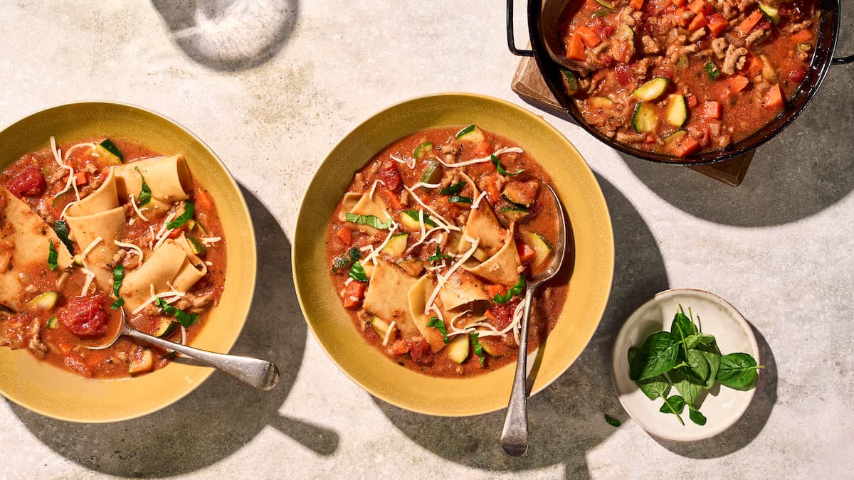 Vegetarische lasagnesoep met tomaat, volkoren lasagnebladen, groente en kaas, geserveerd als warme soep in een kom
