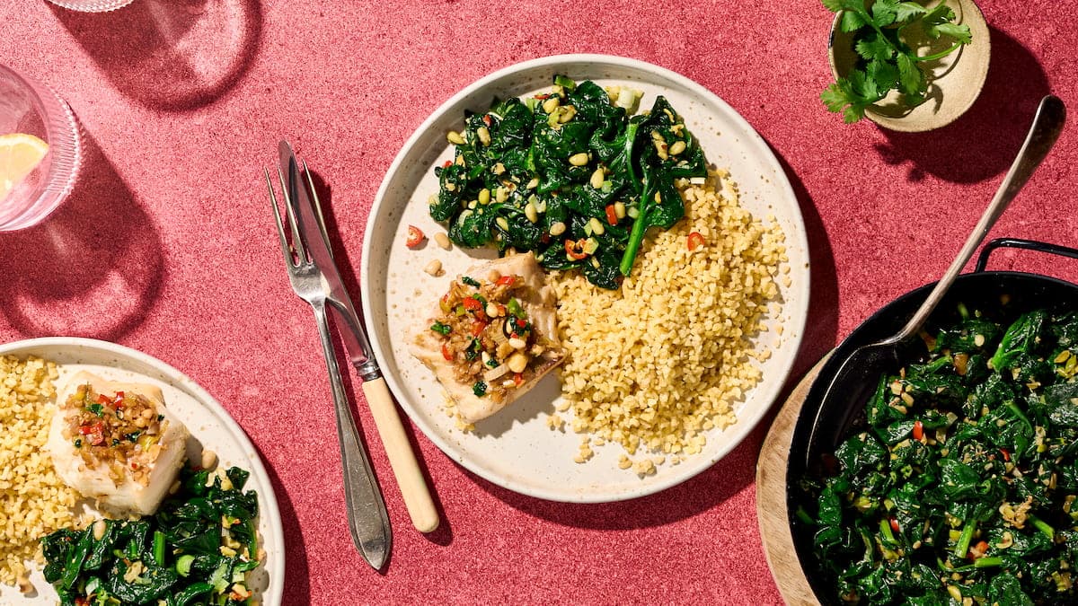 Mahi met dukkah, spinazie en bulgur, geserveerd als kleurrijk gerecht met vis, granen en groene bladgroenten op een bord