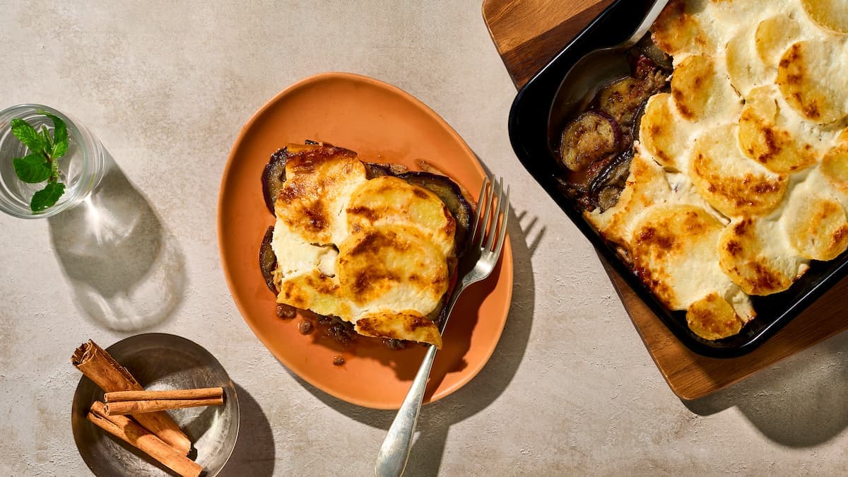 Moussaka met rundertartaar en aubergines geserveerd in een ovenschaal, met laagjes aubergine, gekruid rundvlees en saus