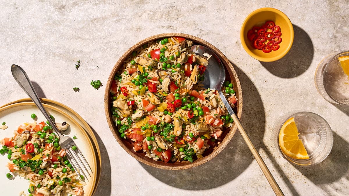 Rijstsalade met mosselen en doperwten, geserveerd als frisse salade met rijst, schelpdieren en groene erwten op een bord