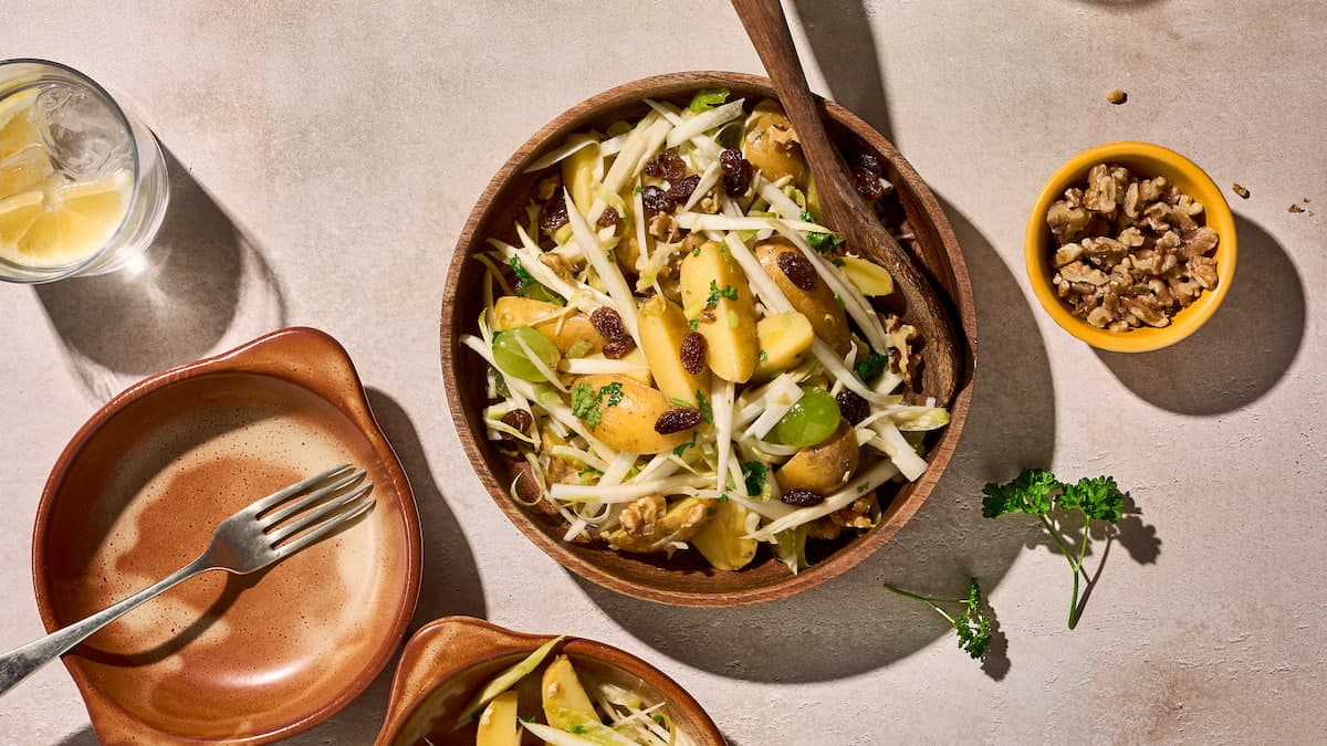 Witlof‑aardappelsalade met rozijnen en noten, geserveerd als frisse salade met witlof, aardappelstukjes en noten op een bord